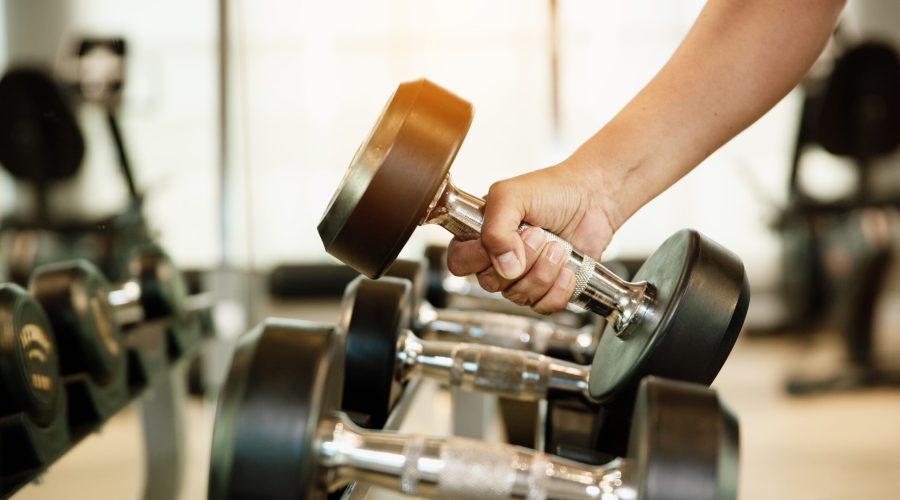 Close,Up,Hand,Holding,Dumbbell,On,Floor,In,Gym,With